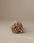 The mushie Multi-Use Cover, featuring a brown and beige leopard print, is shown rolled up on a light beige surface—perfect as a stylish carseat or nursing cover.