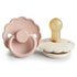 The FRIGG Daisy Natural Rubber Pacifier 2-Pack features two daisy-shaped pacifiers in soft pastels, with one upright showing a natural latex nipple and white base, and the other flat revealing a pale pink front with embossed FRIGG branding.