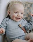 A smiling baby lies on a Mushie Changing Pad Liner.