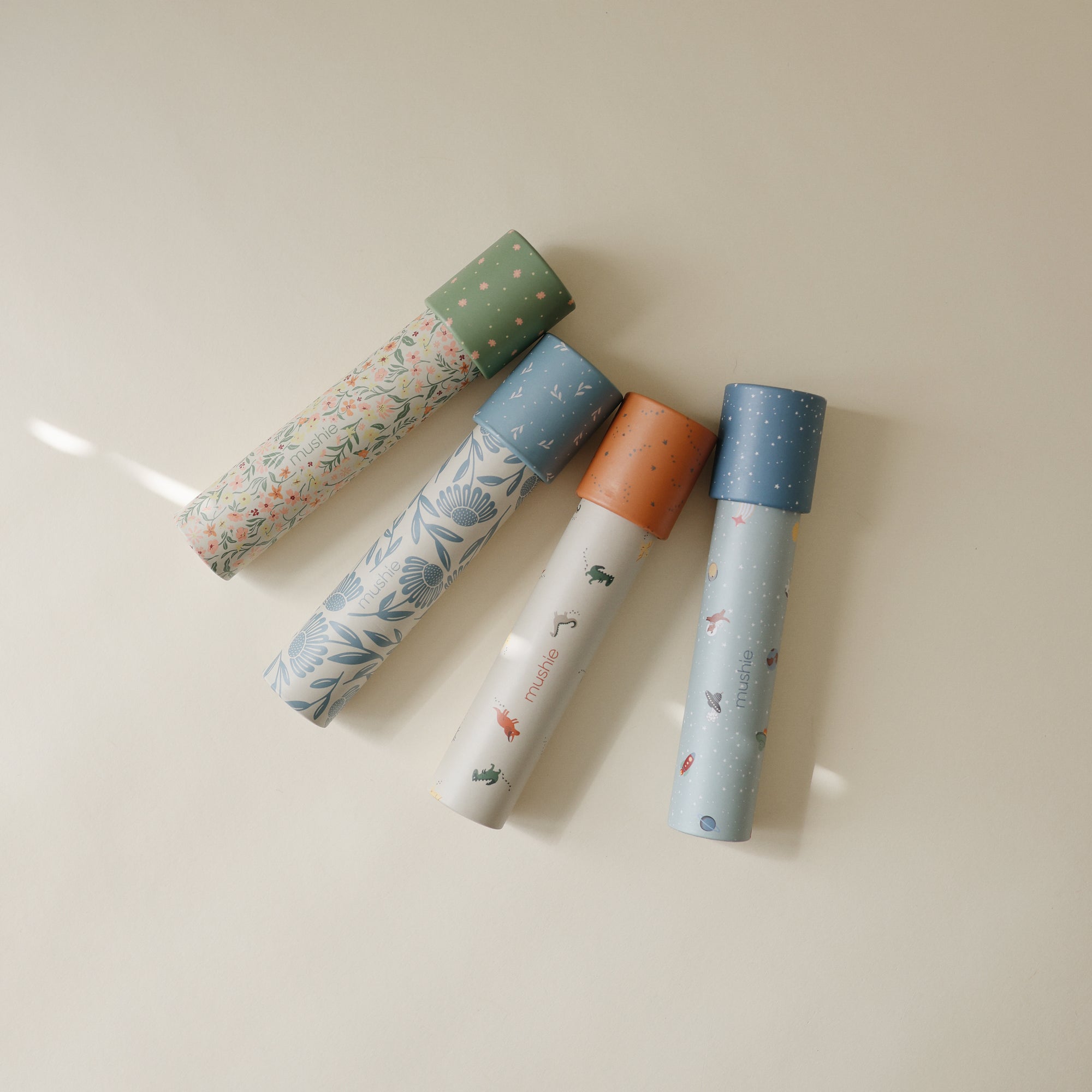 Four mushie Kaleidoscopes with patterned tubes and bright caps, perfect for kids’ play.