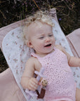 Baby lying on an organic cotton floral Mushie Changing Pad Liner in the grass.