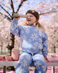 A young child enjoys playing with mushie Kaleidoscopes on a pink outdoor bench.