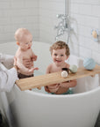 Two small children play with mushie's Nesting Spheres Sensory Toy on a wooden bath tray.