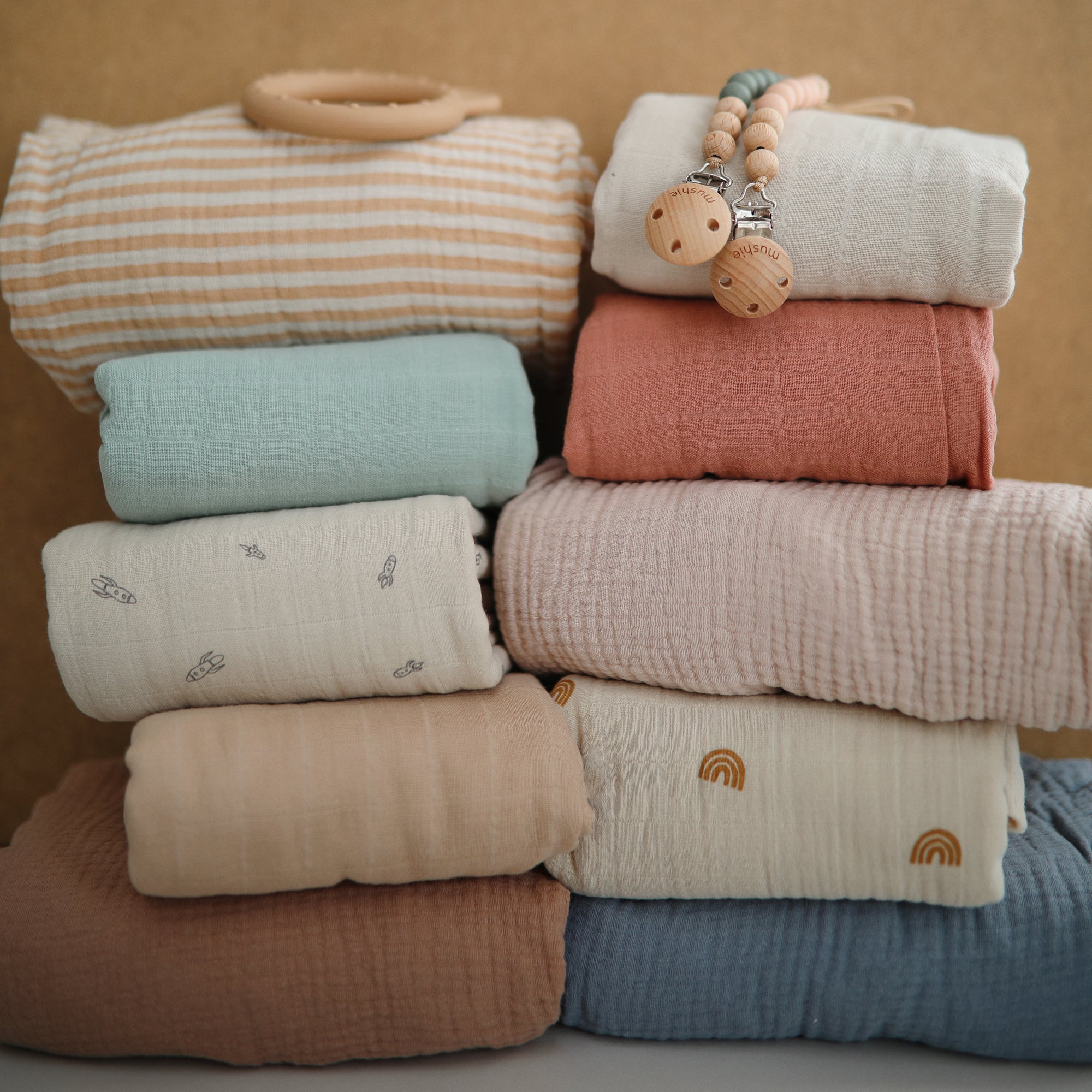 Extra soft mushie muslin crib sheet with wooden pacifier clips stacked on top.