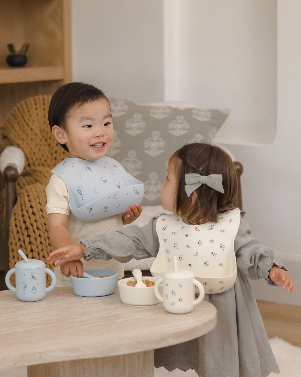 Two toddlers use the Rylee + Cru Feeding Kit Heart Ditsy, smiling together at a small table.