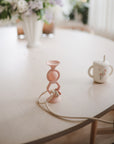 Mushie HexaPop Suction Toy and sippy cup on a table, with flowers in the background.