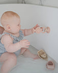 Baby in bath reaches for mushie HexaPop Suction Toy, with sensory toys close by.