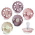 The FRIGG Silicone Pacifier 6-Pack by FRIGG includes pastel pacifiers in pink, lavender, beige, and mauve. Made in Denmark from medical-grade silicone, each features a scalloped shield with heart cutouts; one is shown displaying its nipple.