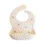 The mushie Bluey x Mushie Silicone Baby Bib features a cream base with cute stars, hearts, flowers, and cartoon animals. With an adjustable pocket design and button fasteners, it’s perfect for fans of adorable mealtime style.