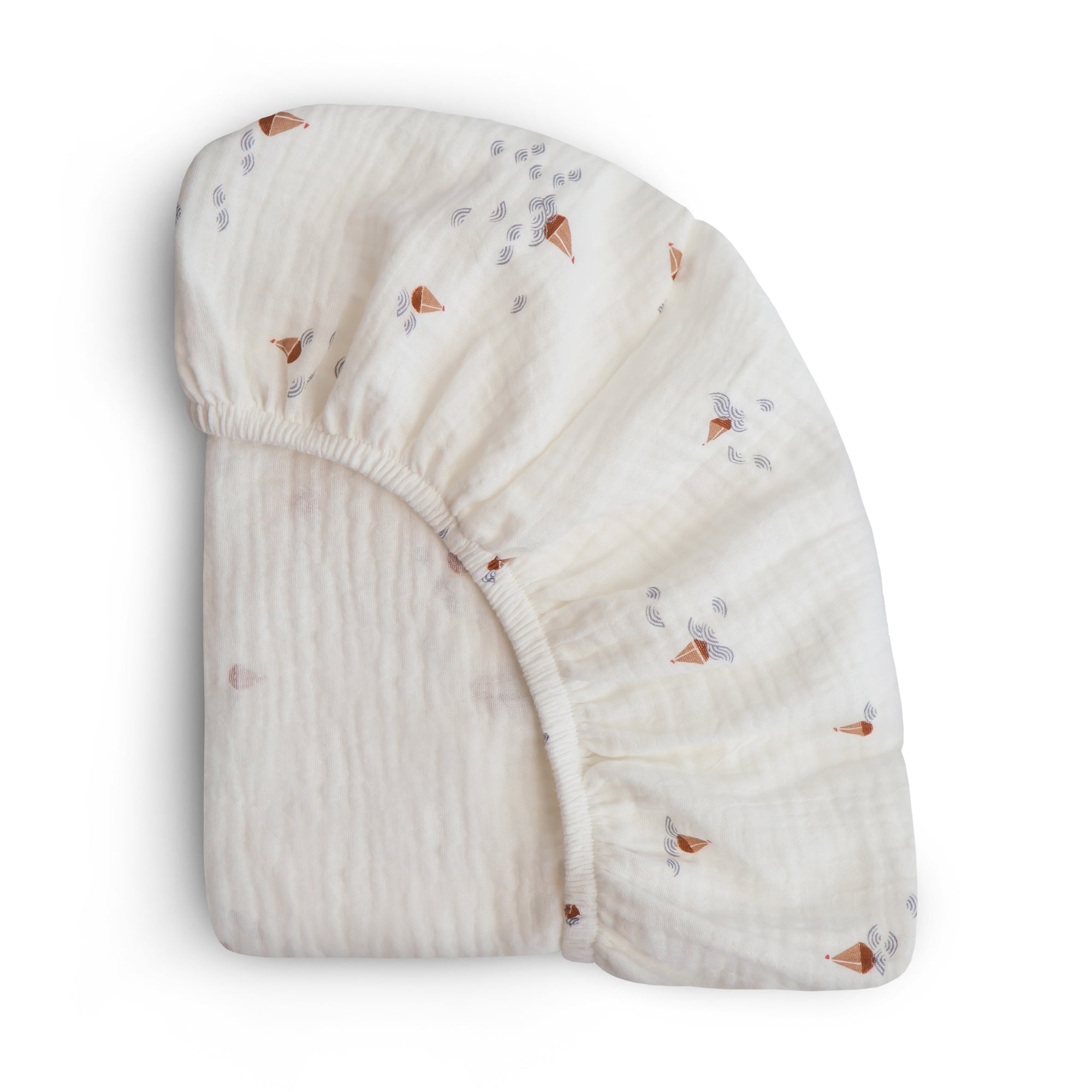 Mushie Extra Soft Bassinet Muslin Crib Sheet, brown and gray print, folded on white background.