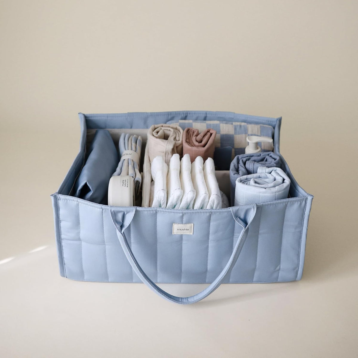 Blue storage caddy with folded clothes on a beige background