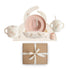 The mushie Deluxe Pink Flowers/Blush Feeding Kit features a floral bib, two-handled cup, bowl with two spoons, sippy cup, plate, and tray—all displayed above a brown gift box tied with a white ribbon.