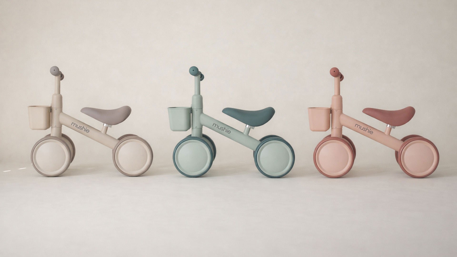 Three Mushie mini bikes lined up side by side against a soft beige background.