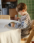 Child eating with chopsticks from mushie Round Dinnerware Bowl at the table.