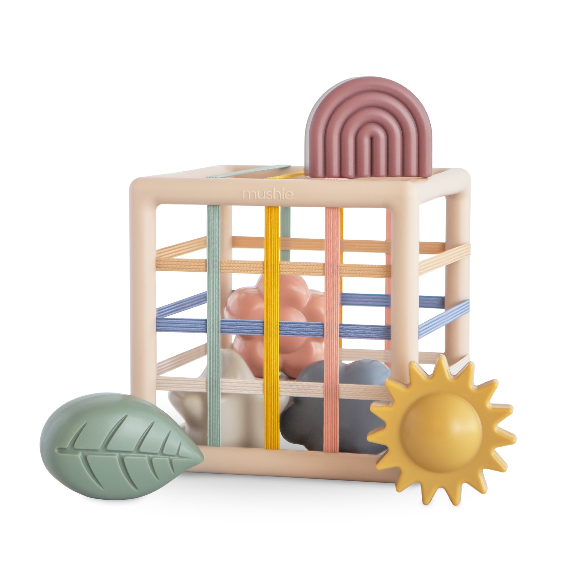 The mushie Elastic Shape Sorter is a pastel toy cube for tactile play and fine motor skills.
