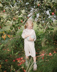 Smiling child uses mushie Lunchbox with compartments under an apple tree.