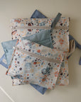 Four mushie Water Resistant Wet Bags with space designs are displayed on blue backgrounds.