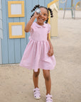 A smiling girl in pink enjoys outdoor imaginative play with a mushie Kaleidoscope.