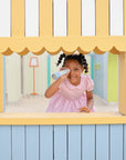 Girl in pink dress enjoys imaginative play with mushie Kaleidoscopes by the window.