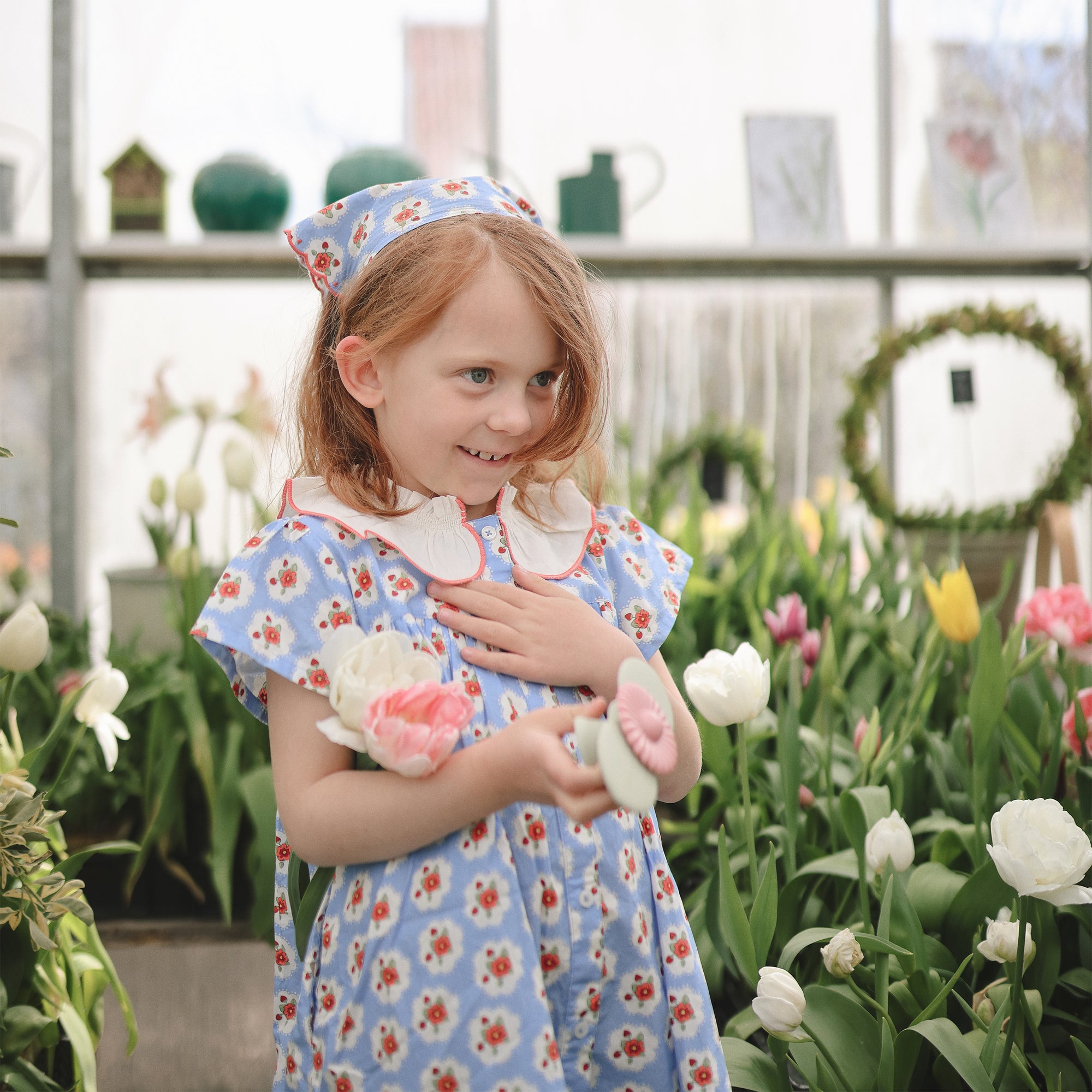 Young girl enjoys tulips while playing with mushie Suction Spinner Toy.