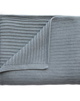 The mushie Knitted Ribbed Baby Blanket is shown neatly folded in light gray, displaying its breathable ribbed knit texture with both front and back sides visible.