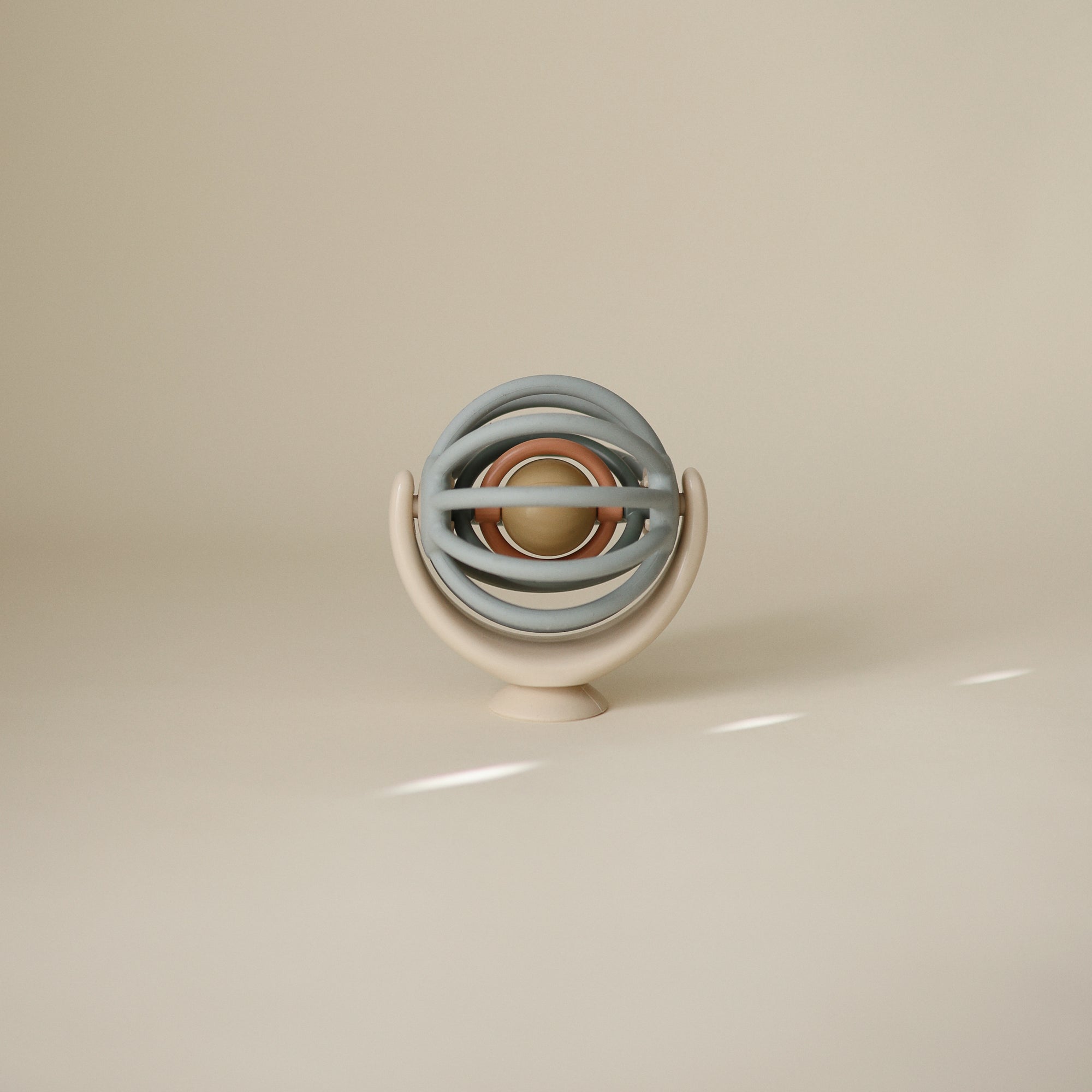 Suction spinner ball toy with stacked circular rings on a beige background