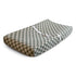 The mushie Extra Soft Muslin Changing Pad Cover, in green and white checks, fits a contoured pad with raised edges and features a white safety strap for added security.