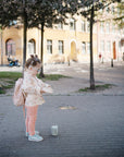 Young girl with glasses carries a mushie Lunchbox with built-in compartments and non-toxic materials.