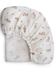 Mushie Extra Soft Bassinet Muslin Crib Sheet in white with pink floral pattern, neatly folded.