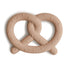 The mushie Pretzel Teether is a light brown, non-toxic silicone baby teether shaped like a pretzel, featuring small raised rectangles that look like salt pieces.