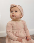 Baby in Rylee + Cru Ribbed Long Sleeve Dress Dusty Rose Microstripe sits on floor looking up.