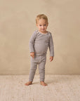 Toddler in Rylee + Cru Ribbed Tee + Legging Set Slate Microstripe stands barefoot on a rug.