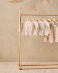 Six Rylee + Cru Cloud Stripe tees hang on a rack against a beige wall with star decorations.