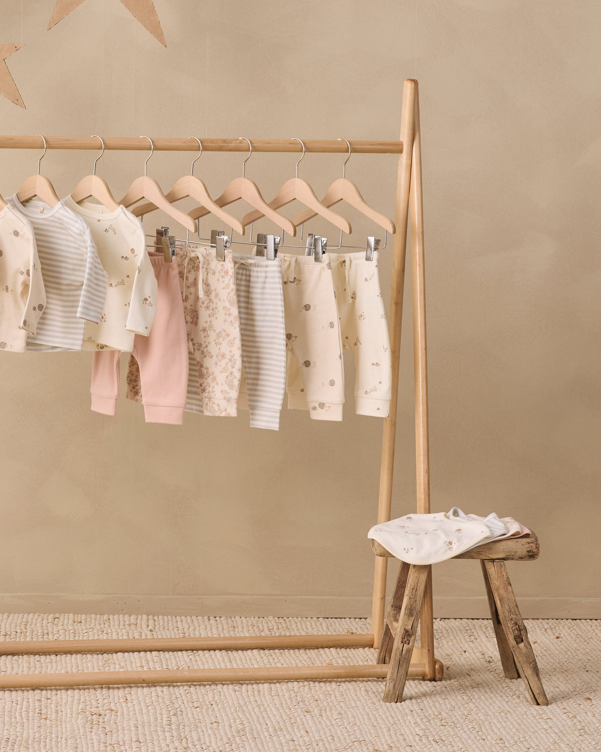 Rylee + Cru Drawstring Pant Cloud Stripe hangs on rack, stool near, beige background.