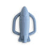The mushie Rocket Rattle Teether is a blue silicone baby teething toy shaped like a rocket, featuring two textured side handles and "mushie" embossed at the center, shown on a white background.