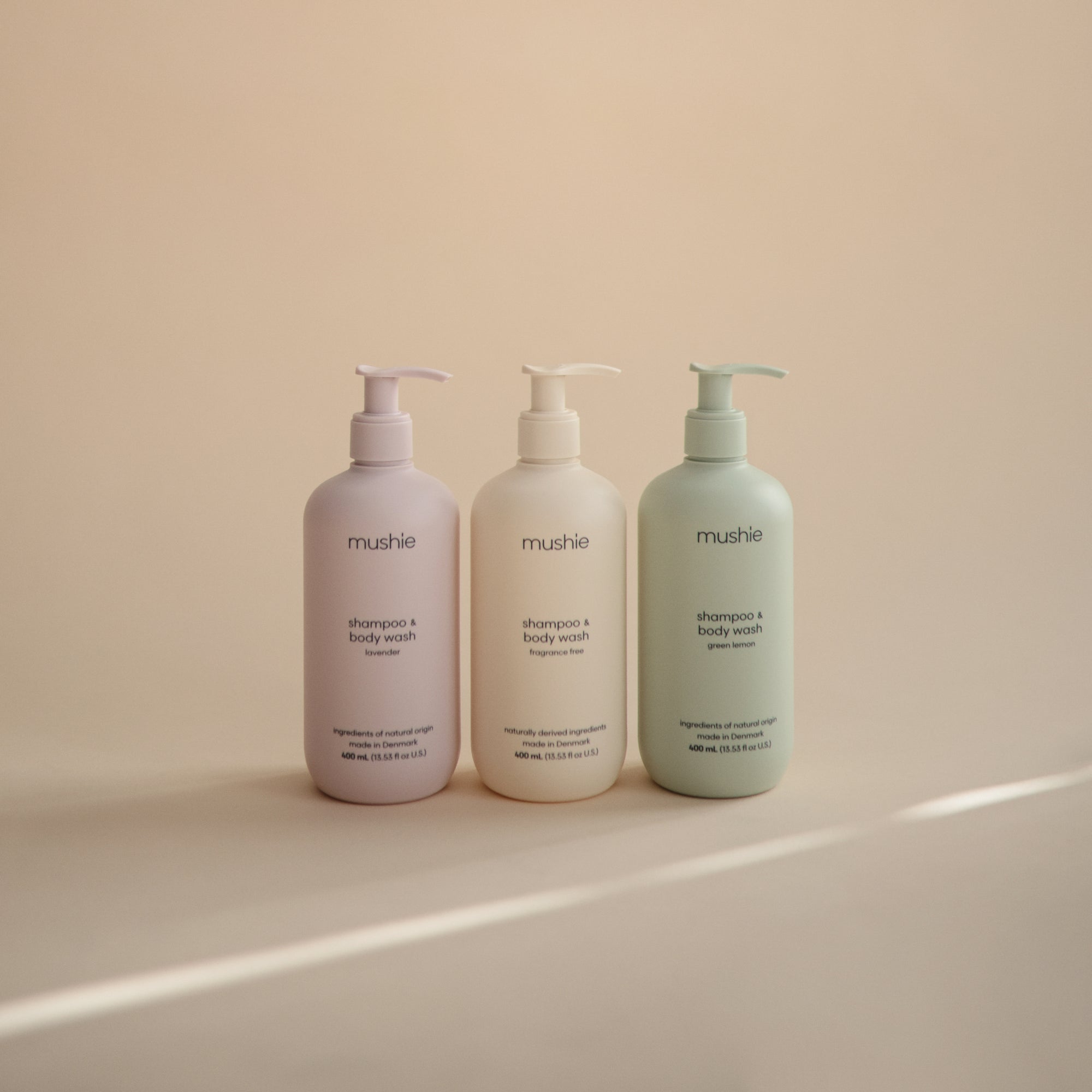 Three mushie Baby Shampoo &amp; Body Wash bottles for delicate skin on a beige background.