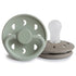 The FRIGG Moon Silicone Pacifier 2-Pack by FRIGG, shown in Sage upright and Portobello flat with the nipple up, features medical grade silicone and round shields with ventilation holes—making them perfect baby essentials.