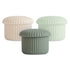 Set of three mushie Silicone Baby Food Containers with matching lids in beige, mint green, and sage green; round, ribbed design made from food-grade silicone, displayed on a white background.