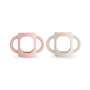 Two mushie Silicone Bottle Handles in Blush and Shifting Sand are shown side by side on a white background. These baby bottle accessories feature wide openings and rounded bases for universal fit.