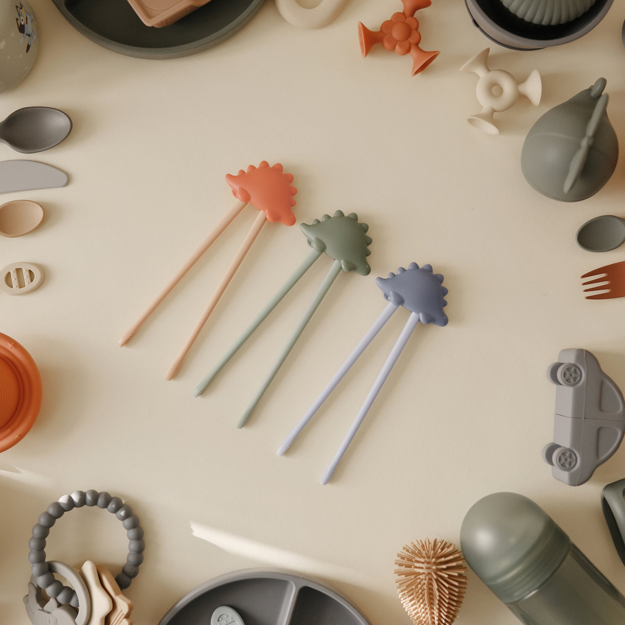 Three mushie Training Chopsticks with pastel baby self-feeding utensils.