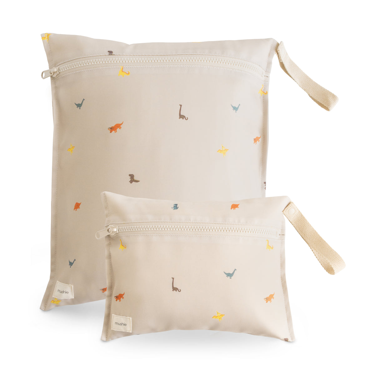 Two beige mushie Water Resistant Wet bags with a dinosaur print and side carry straps.
