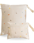 Two beige mushie Water Resistant Wet bags with a colorful dinosaur pattern and side carry straps.