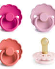 Four pink scalloped-edge FRIGG Natural Rubber Pacifiers, one with the nipple visible.