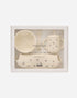 Mushie x Quincy Mae Feeding Kit in a white gift box with a clear window, containing a cream-colored bowl, sippy cup with straw, spoon, and small footmuff.
