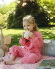 A young child drinks from a cup near a mushie Diaper Caddy outdoors.