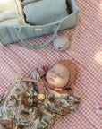 Baby on a pink checkered blanket with FRIGG Andersen Fairytale Natural Rubber Pacifier.