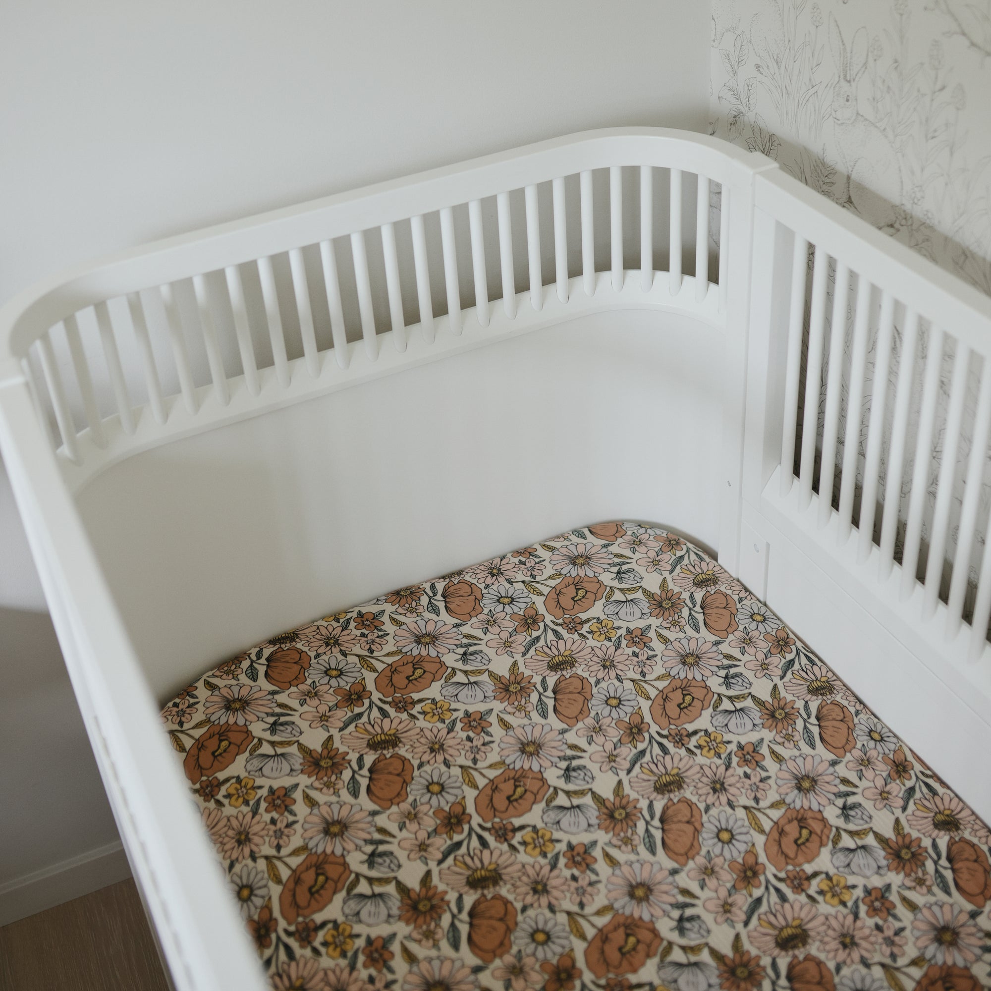 White crib with mushie Extra Soft Muslin Crib Sheet in a bright, neutral nursery.