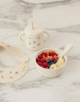 Rylee + Cru Feeding Kit Heart Ditsy with bowl, cup, spoon, bib & fruit on marble.