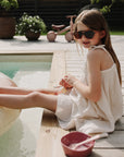 Girl in sunglasses by pool, ice cream and mushie Square Dinnerware Bowls by her side.