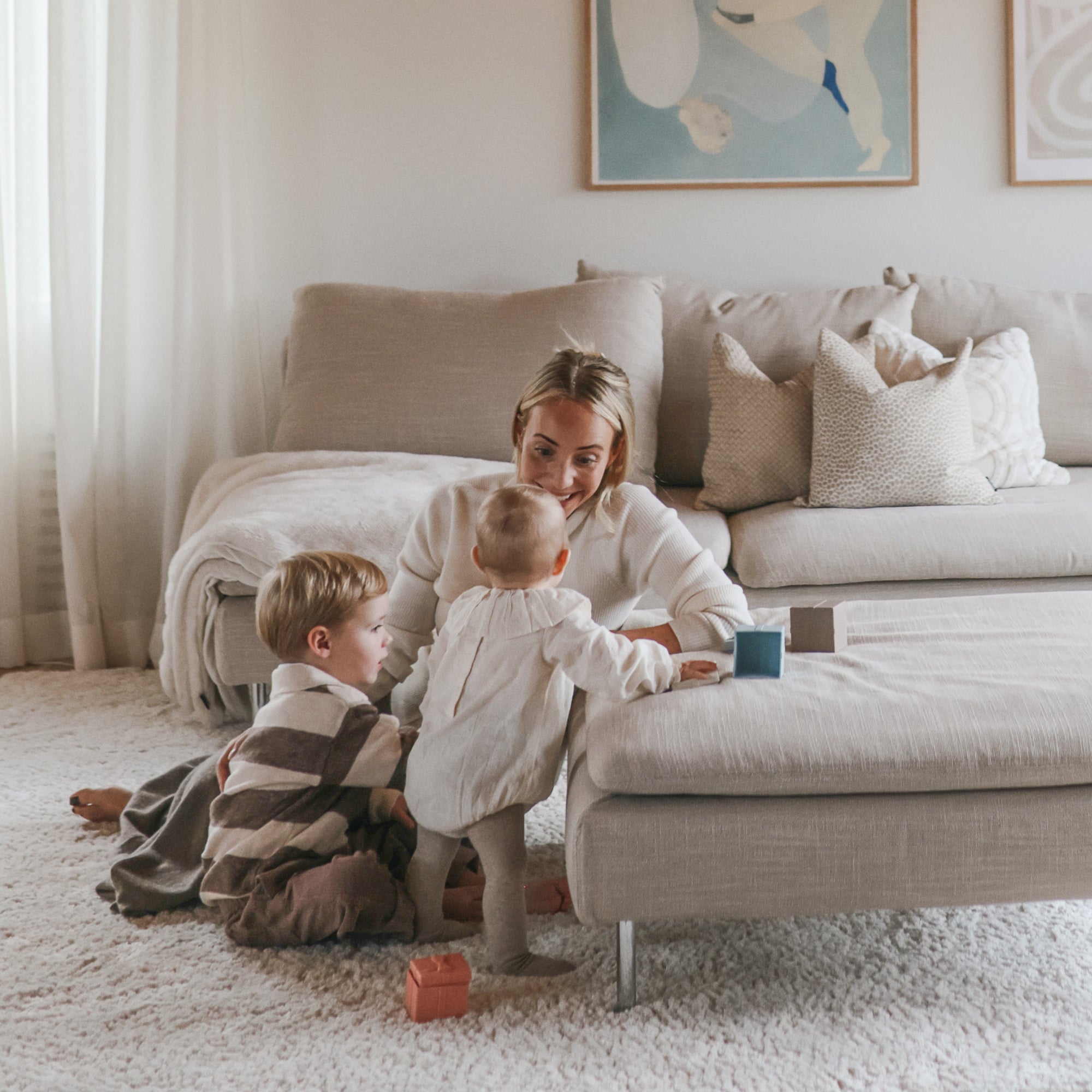 A woman and two kids play with mushie's Mix and Match Toy, building fine motor skills.